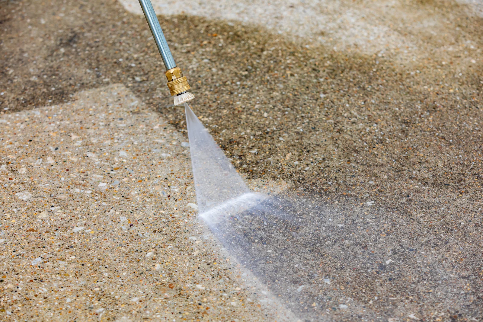 Close-up pressure washing of a concrete driveway surface